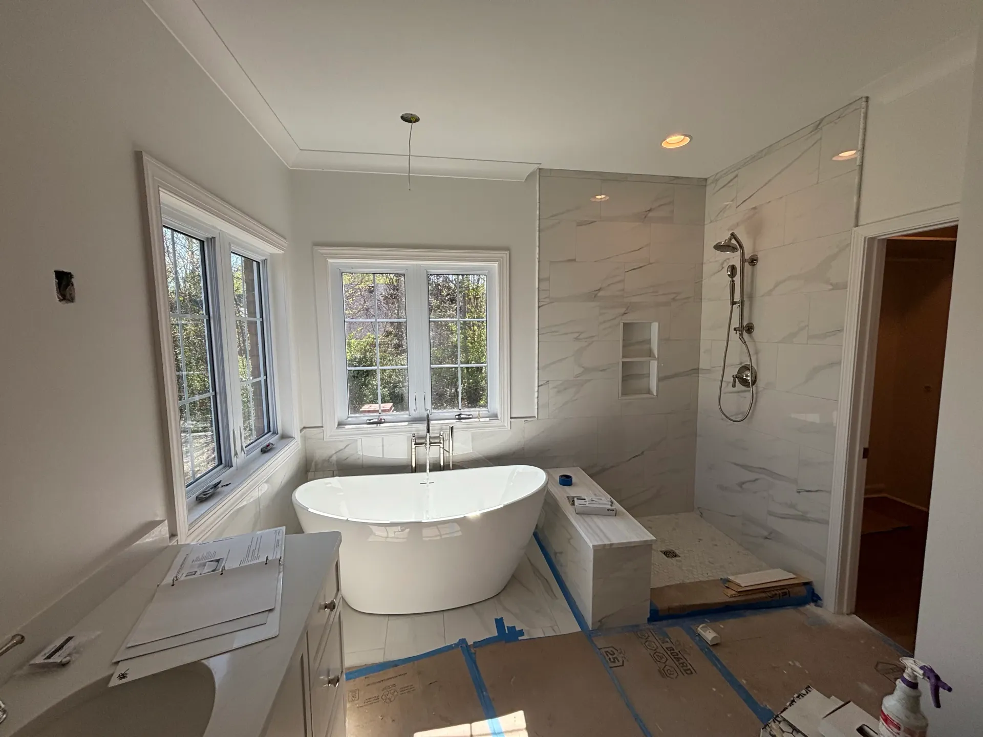 Bathroom remodel with freestanding tub, marble shower wall, and windows