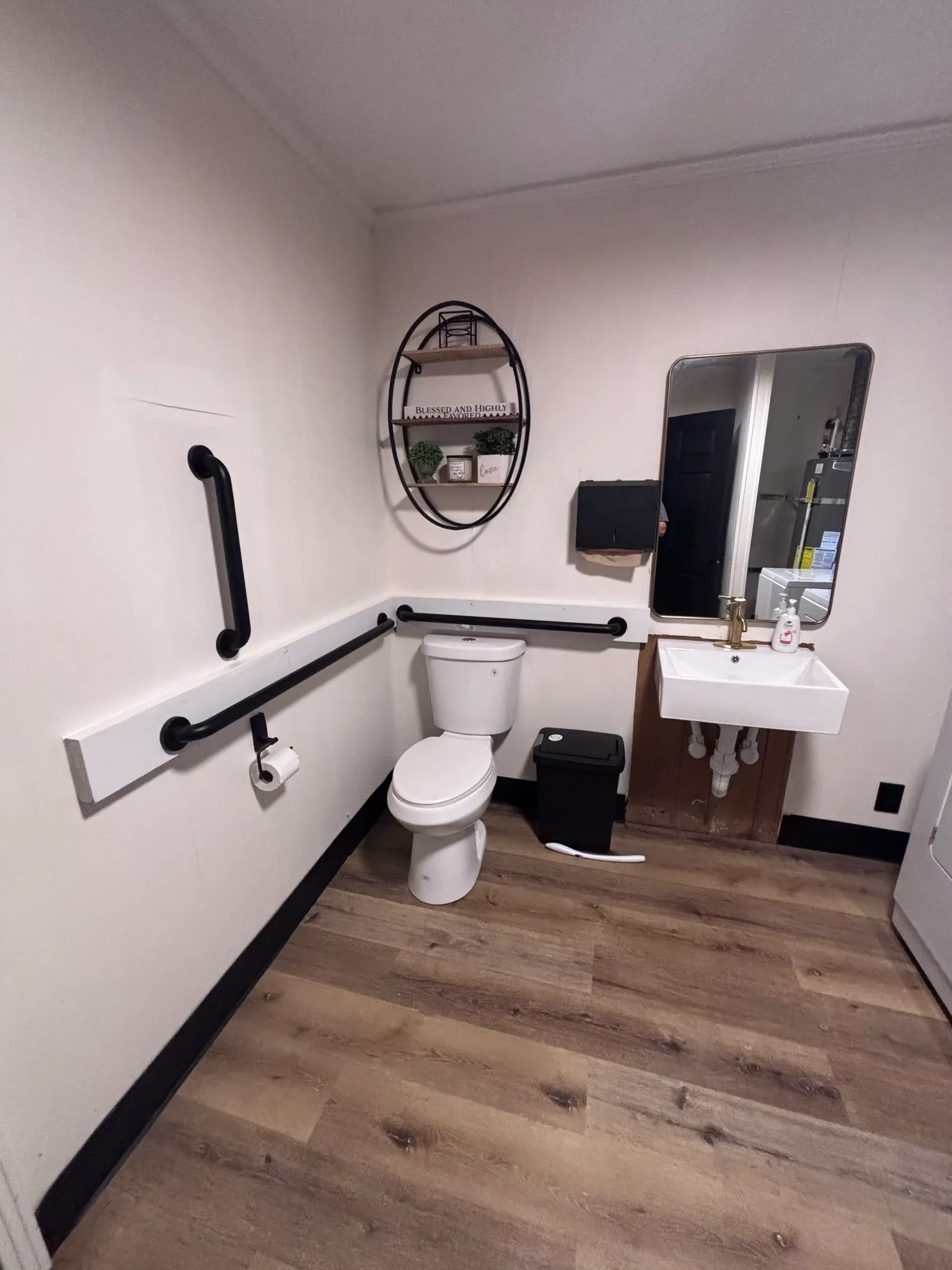 Accessible bathroom remodel with grab bars, pedestal sink, and new flooring